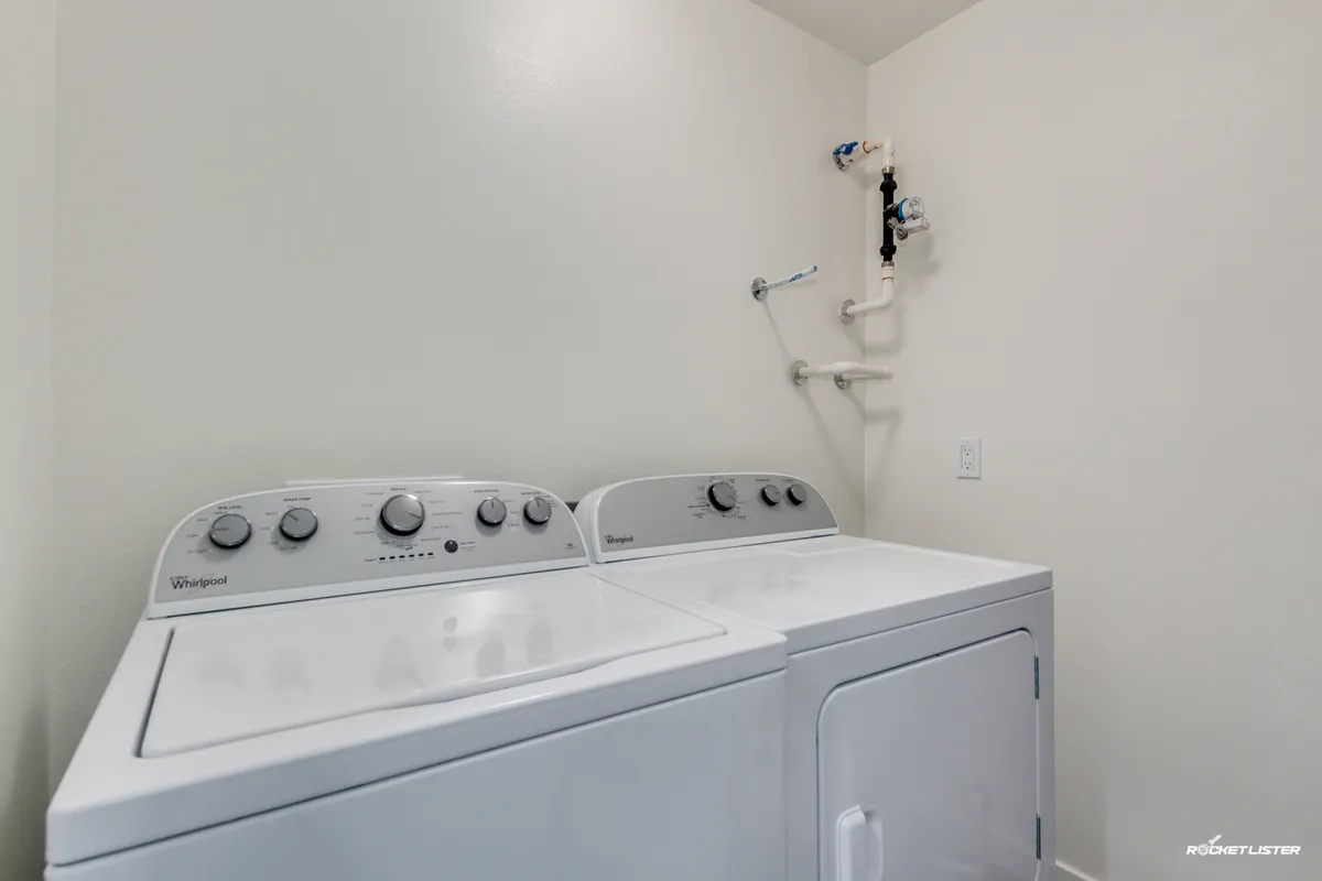 A laundry area with a front-loading washing machine and dryer, arranged in a clean, organized setting. The straightforward design highlights the convenience and practicality of in-unit laundry facilities for long-term guests.